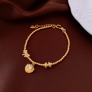 Detail of 18k gold plated bracelet with cat eye stone, bow charm and shell pendant