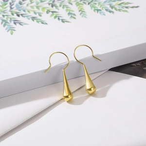 Close-up of golden teardrop earrings with polished metallic finish on book background