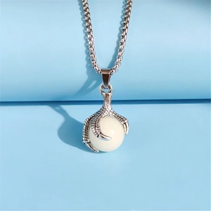 Detailed view of vintage silver dragon claw necklace holding a white bead on blue background