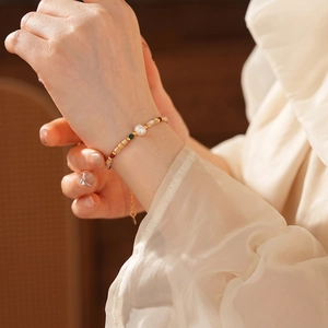 Bracelet vintage en perles de coquillage avec perles dorées au poignet d'une femme