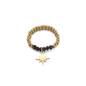 Detailed macro view of beaded stretch ring with gold beads and star pendant charm
