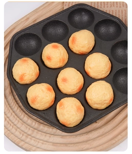 Vista dettagliata di polpette takoyaki dorate in una teglia antiaderente nera a 12 fori