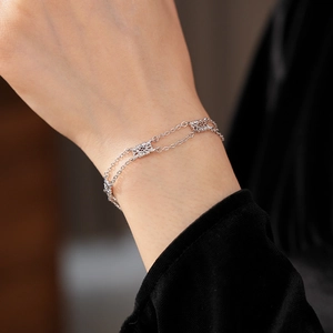 Detailed macro of a silver floral hollow bracelet with double chain layers on wrist