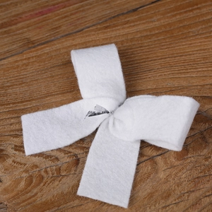 Macro detail of white felt Christmas tree bow ornament on a rustic wooden background