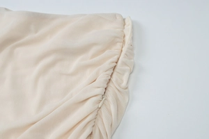 Detail view of beige mesh fabric with side ruching and invisible zipper closure