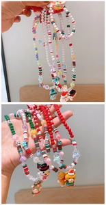 Detail showing handmade Christmas beaded necklaces with Santa, snowman, and reindeer charms