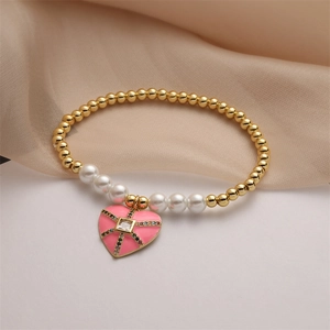 Dettaglio del ciondolo a cuore rosa con zirconi su bracciale di perle e oro