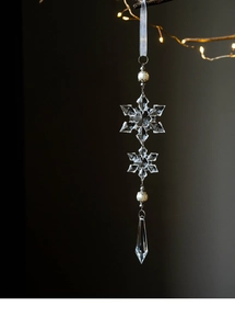 Macro shot of clear acrylic snowflake ornaments with white pearls on a festive branch