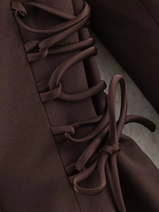 Detail of the dark brown lace-up side design with tie closure on a stylish blazer coat