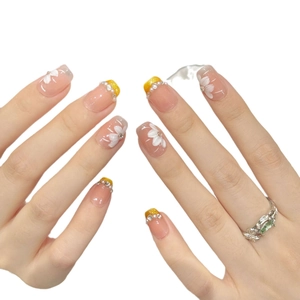 Handmade nude press-on nails with white floral patterns and sparkling gold glitter