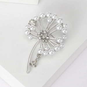 Détail macro d'une broche pissenlit avec perles blanches et cristaux sur base argentée