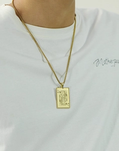 Detail of gold necklace with King of Hearts poker card pendant on male model shirt