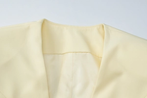 Detailed macro view of the collar stitching and woven fabric on this pale yellow jacket