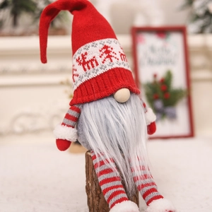 Close-up of knit Christmas gnome with reindeer patterns and striped legs on wood