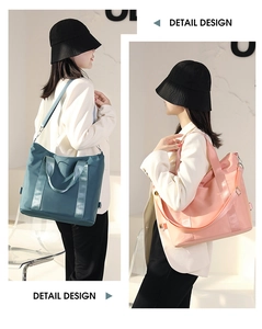 Detail design of a large capacity nylon crossbody bag in dark cyan and light pink colors