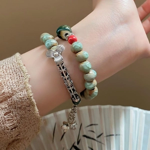 Gros plan d'un bracelet à double rangée avec perles vertes et pendentif fleur argenté