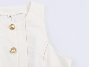Détail de haut sans manches blanc avec boutons dorés, coutures brunes et étiquette M