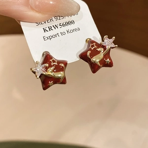 Detail of red star earring featuring a golden cat pattern and sparkling cubic zirconia