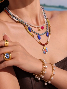 Detail of layered jewelry set featuring natural pearls and colorful beaded floral pendants