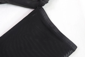 Gros plan sur le tissu en maille noire transparente et les coutures de la robe moulante
