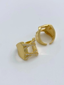 Detail of gold X-shaped crisscross ring with pavé cubic zirconia on white background