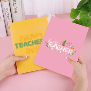 Close-up of yellow and pink pop-up 3D cards with Teacher's Day greetings on a desk