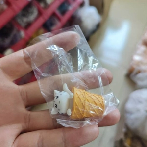 Close-up of white cat ice cream figurine held in hand with miniature cone detail