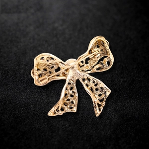 Luxurious gold bowknot brooch with intricate hollow design and sparkling rhinestones