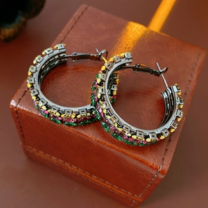 Detailed shot of vintage rainbow zircon hoop earrings on a brown leather jewelry box
