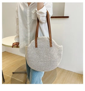 Close-up of the cross-stitched leather handle on this large round woven straw bag