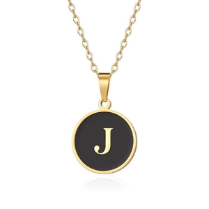 Macro di una collana dorata con ciondolo rotondo nero e lettera J in metallo lucido