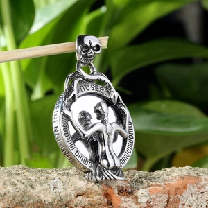 Close-up of silver punk skull pendant with Memento Mori engraving on metal surface