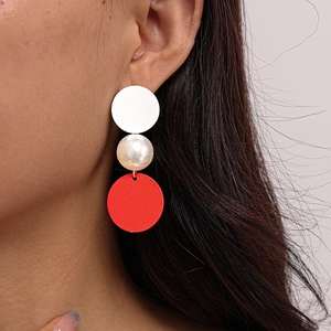Close-up of asymmetrical red and white drop earrings with faux pearls on model