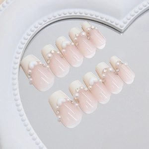 Short ballet press-on nails with white French tips, pearls, and heart charms