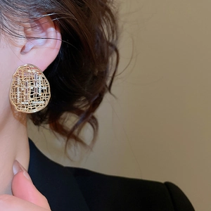 Gros plan d'élégantes boucles d'oreilles ovales dorées avec des pierres de zircone