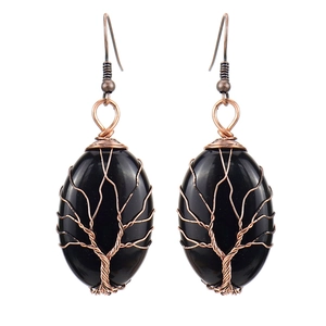 Macro detail of handmade bronze wire-wrapped tree of life earrings with black stone