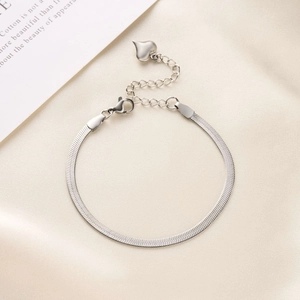 Polished silver flat snake chain bracelet with heart charm on soft satin background