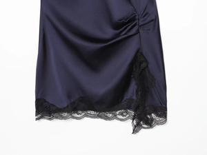 Détail de robe en satin avec dentelle noire, fronçage latéral et fente bleu marine