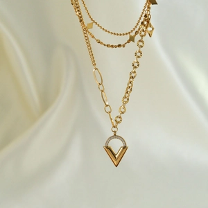 Detail of layered gold V-pendant necklace with zircons on elegant silk background
