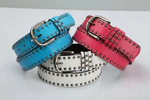 Detail of studded faux leather punk belts in blue, pink, and white with metal buckles