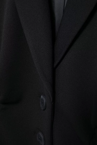 Detail of black blazer collar with textured fabric and two dark button accents