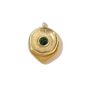 Detail of round gold pendant featuring green malachite stone and sunburst texture