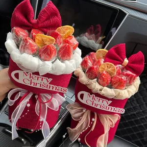 Christmas gift box with red knitted fabric wrap, strawberries, and Merry Christmas tag