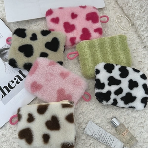 Flat lay of colorful plush heart-patterned coin pouches on a soft white faux fur background