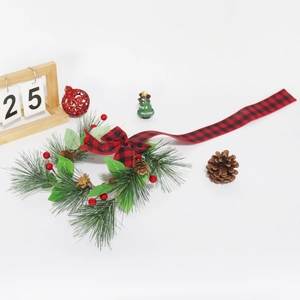 Detail of Christmas wreath featuring buffalo plaid bow, red berries and pine needles