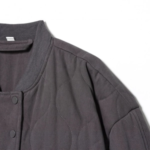 Deep grey quilted bomber jacket featuring detailed stitching and matte metal buttons