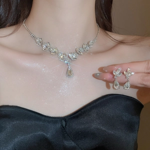 Close-up of sparkling waterdrop pendant necklace and matching earrings on a model