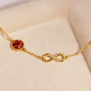 Detail eines 14k Gold Infinity-Armbands mit Basketball-Anhänger auf Samtuntergrund