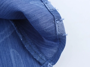 Detailed macro view of blue denim jacquard fabric texture and raw fringe edge stitching