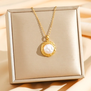 Golden baroque pearl clover necklace on champagne silk gift box background